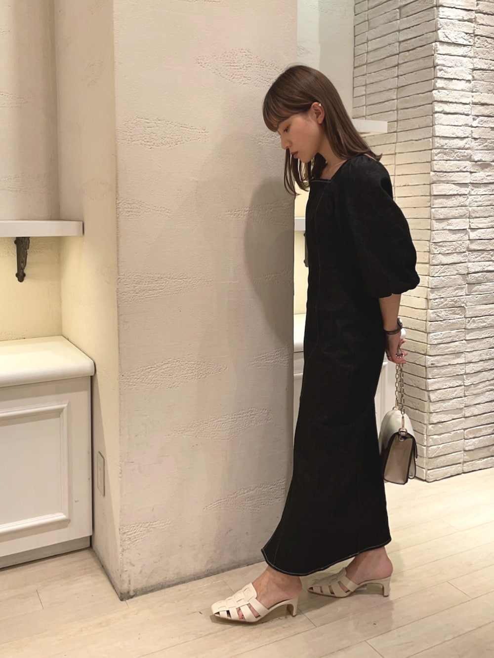 ブラック系のワンピース、ホワイト系のサンダル、ベージュ系のショルダーバッグを着用したレディースの夏コーディネートの2枚目の写真