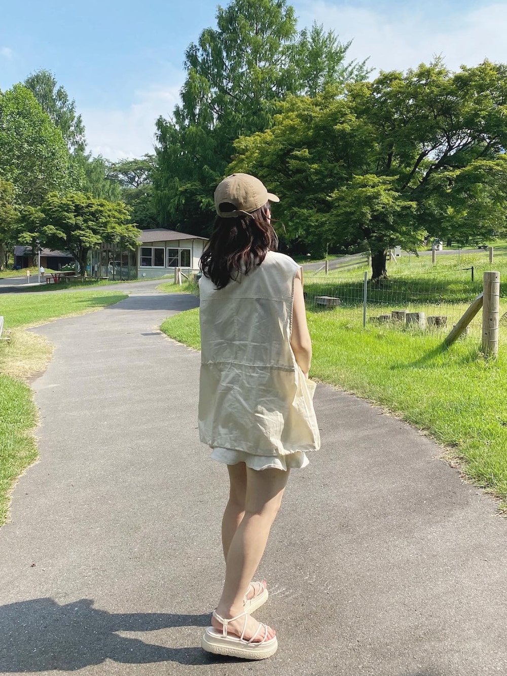 ホワイト系のミリタリージャケット、ホワイト系のデニムスカート、ブラウン系のキャミソールを着用したレディースの夏コーディネートの3枚目の写真