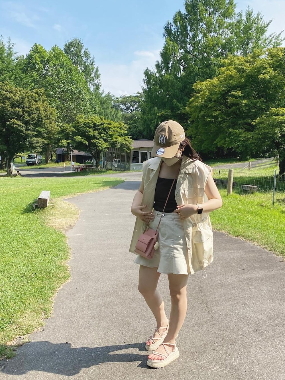 ホワイト系のミリタリージャケット、ホワイト系のデニムスカート、ブラウン系のキャミソールを着用したレディースの夏コーディネートの2枚目の写真