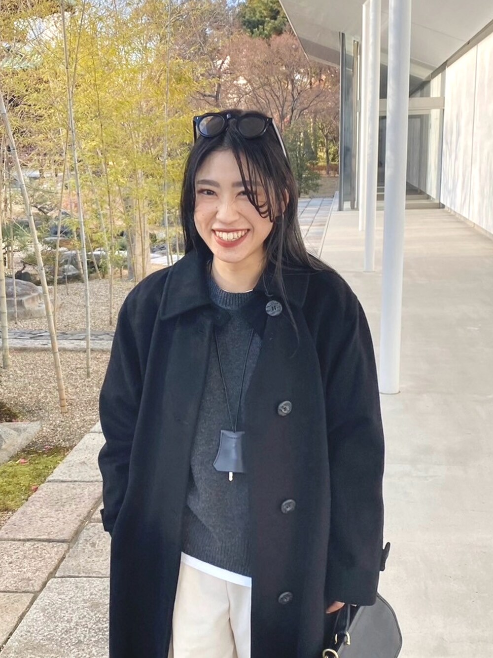 グレー系のニット/セーター、ホワイト系のパンツ、ブラック系のモカシン/デッキシューズを着用したレディースの冬コーディネートの2枚目の写真