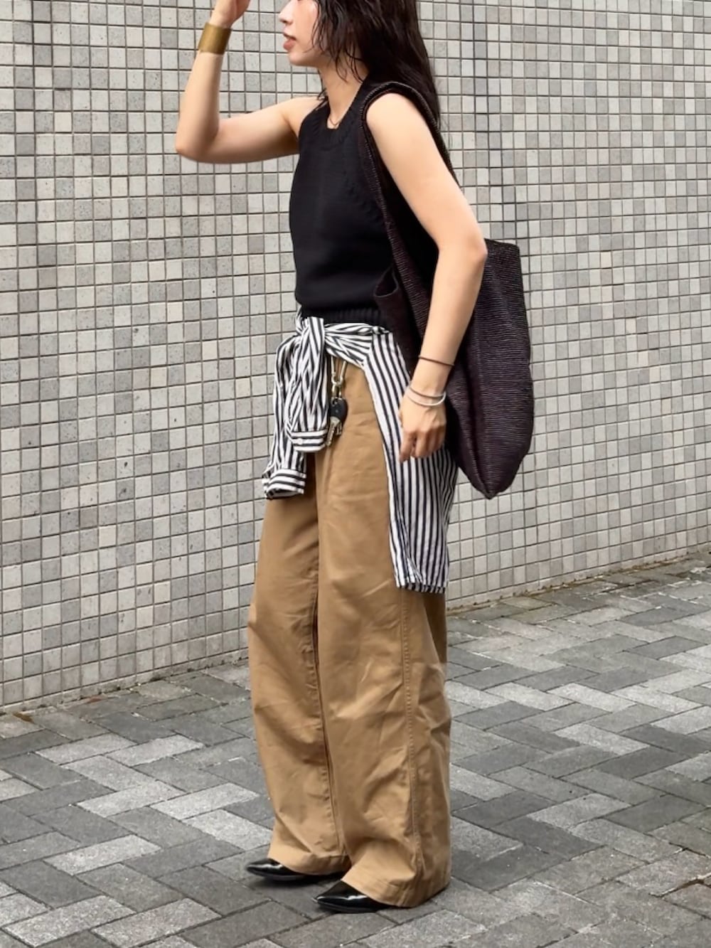 ベージュ系のチノパンツ、ブラック系のニット/セーター、ブラウン系のエコバッグ/サブバッグを着用したレディースの夏コーディネートの2枚目の写真