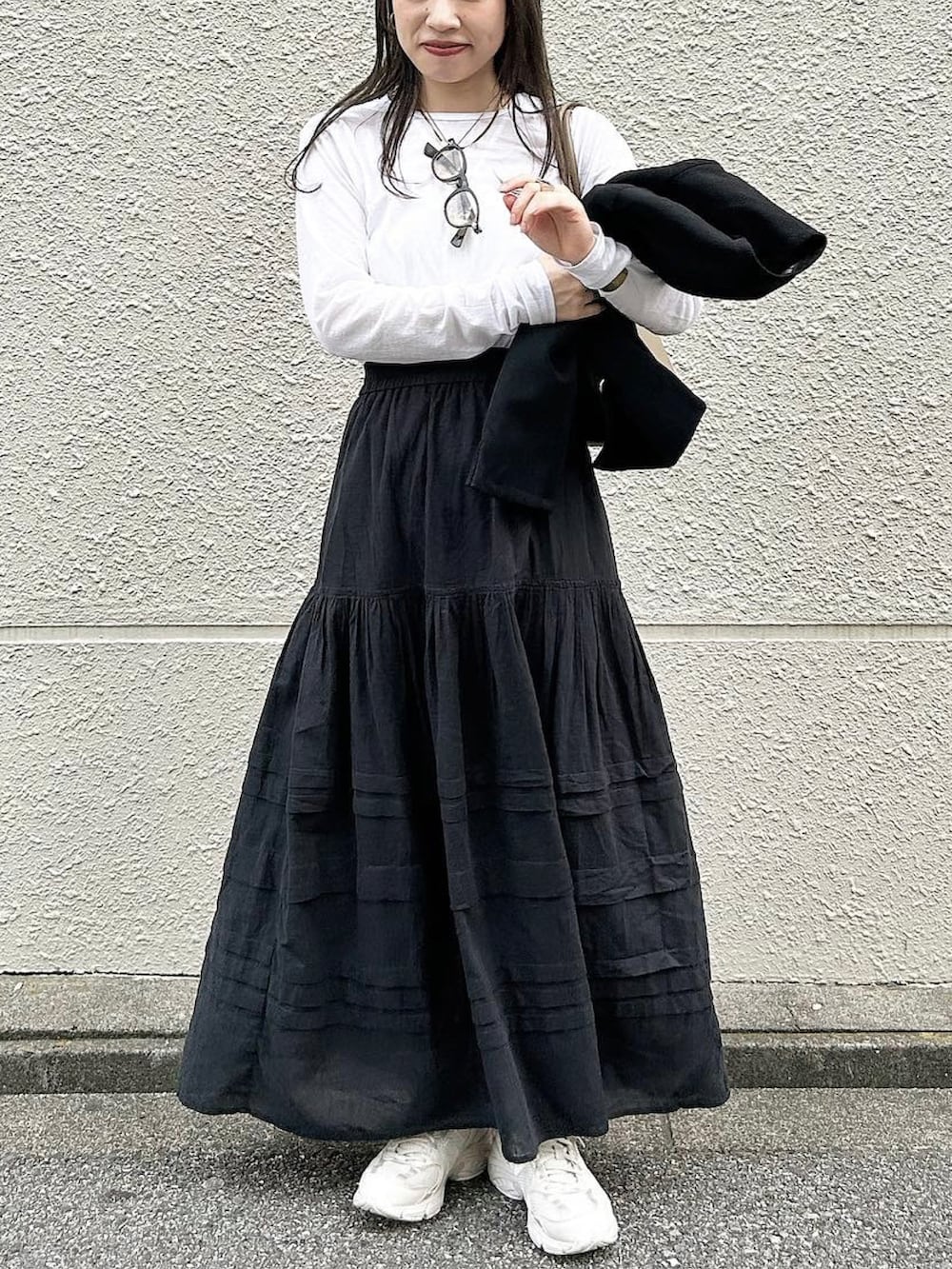 ブラック系のスカート、ホワイト系のスニーカー、ホワイト系のTシャツ/カットソーを着用したレディースの夏コーディネートの2枚目の写真