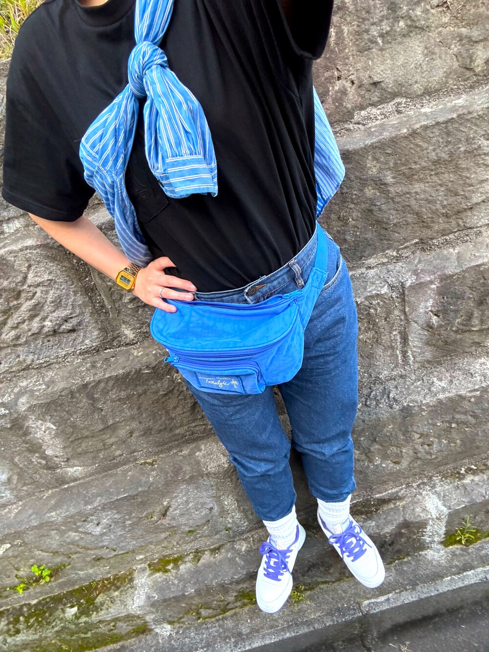 ブラック系のTシャツ/カットソー、パープル系のボディバッグ/ウエストポーチ、ブルー系のデニムパンツを着用したレディースの春コーディネートの2枚目の写真