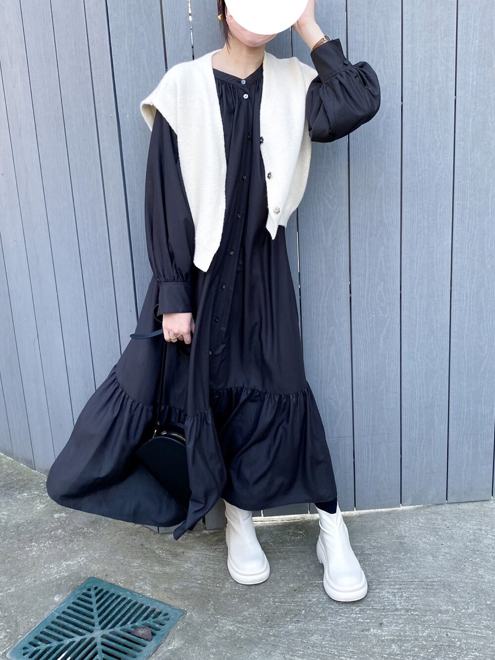 ブラック系のワンピース、ホワイト系のブーツ、ブラック系のショルダーバッグを着用したレディースの冬コーディネートの2枚目の写真