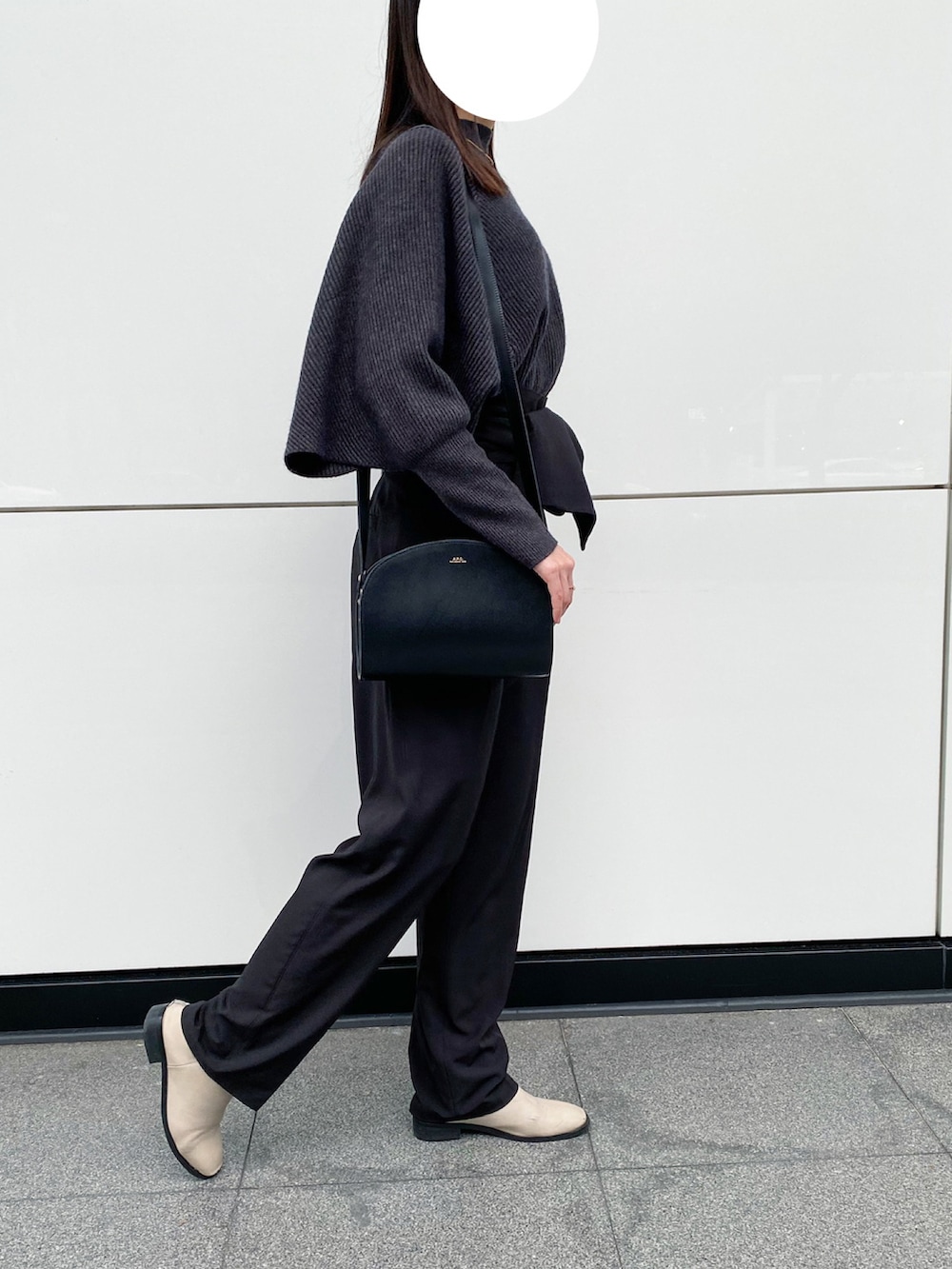 グレー系のニット/セーター、ブラック系のショルダーバッグ、ブラック系のスラックスを着用したレディースの春コーディネートの2枚目の写真
