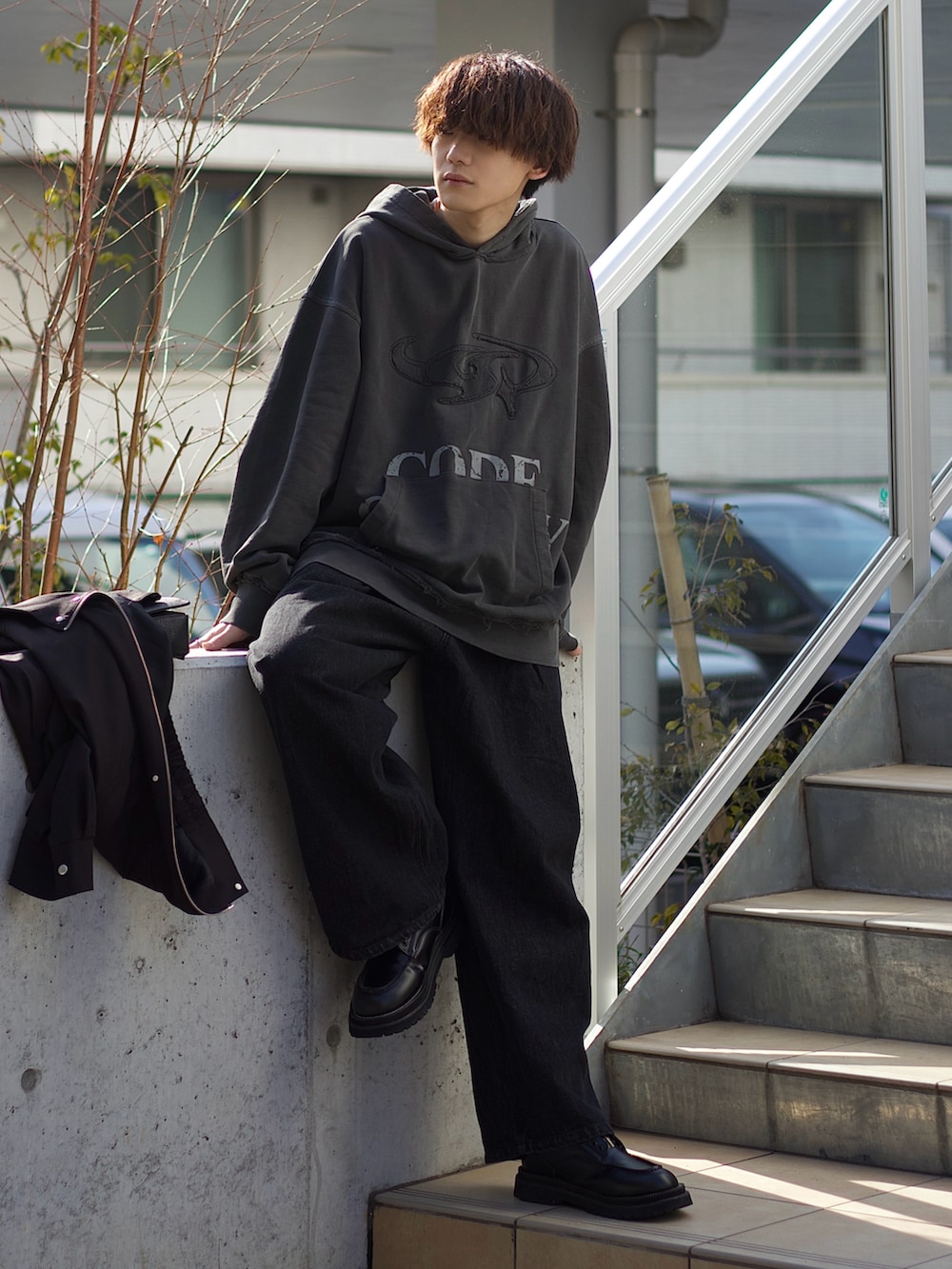 ブラック系のブルゾン、ホワイト系のタンクトップ、ブラック系のデニムパンツを着用したメンズの春コーディネートの3枚目の写真