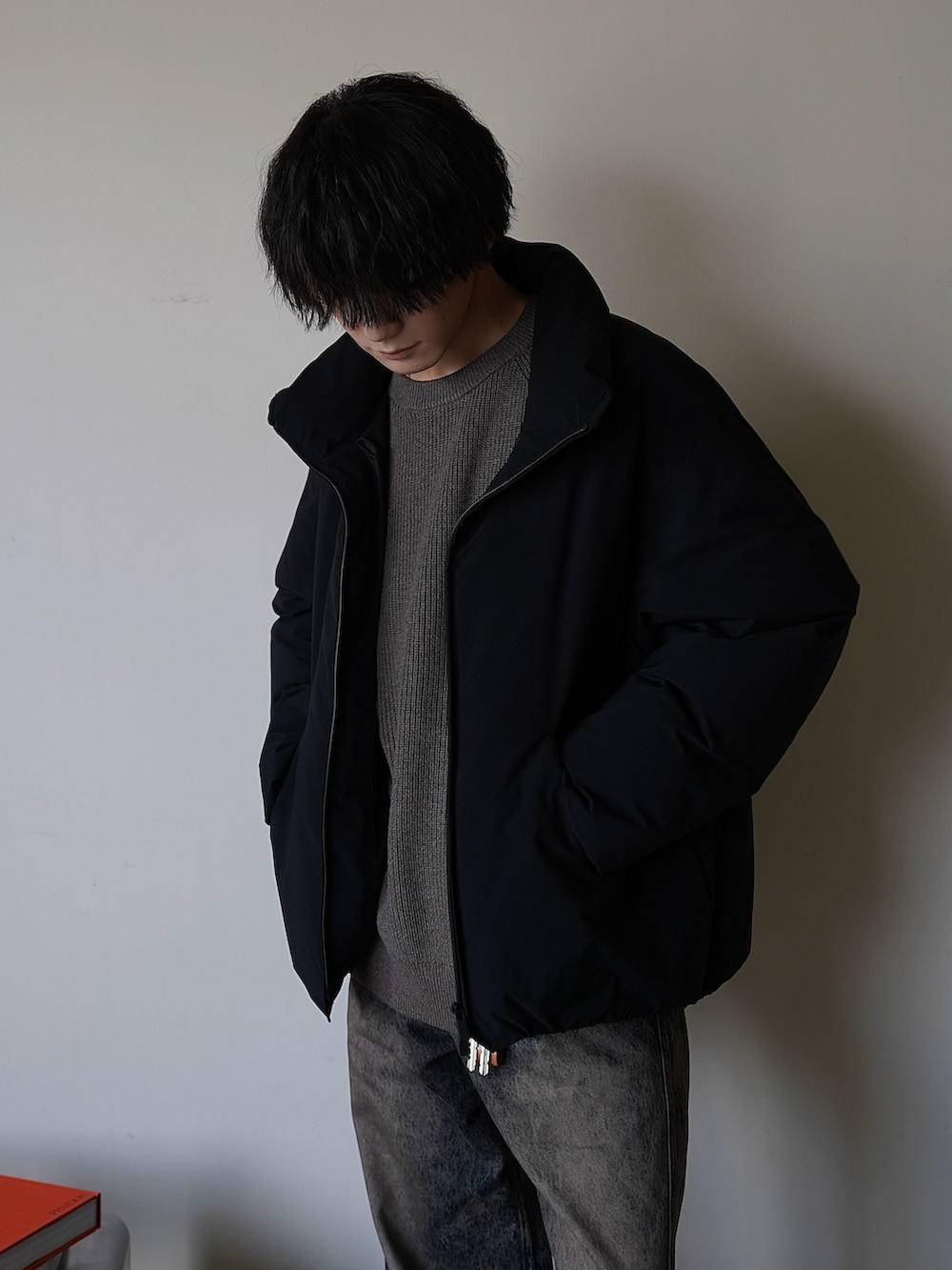 ブラック系のダウンジャケット/コート、ブラウン系のニット/セーター、ブルー系のデニムパンツを着用したメンズの秋コーディネートの2枚目の写真