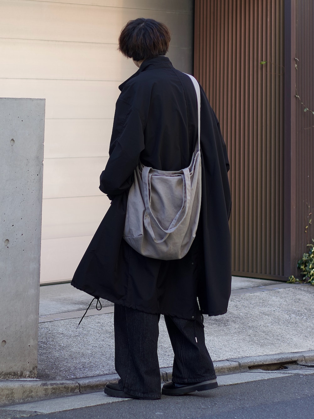 ブラック系のモッズコート、グレー系のベスト、ホワイト系のタンクトップを着用したメンズの春コーディネートの2枚目の写真