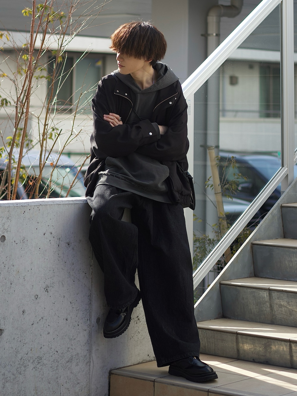 ブラック系のブルゾン、ホワイト系のタンクトップ、ブラック系のデニムパンツを着用したメンズの春コーディネートの2枚目の写真