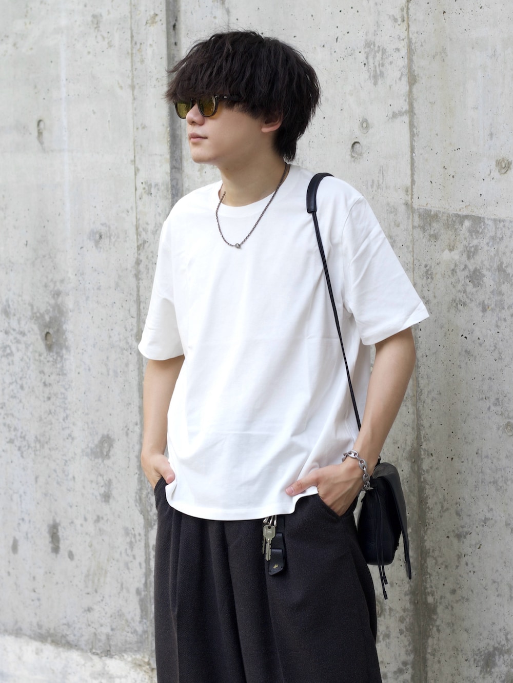 ホワイト系のTシャツ/カットソー、グレー系のスラックス、ブラック系のショルダーバッグを着用したメンズの夏コーディネートの3枚目の写真