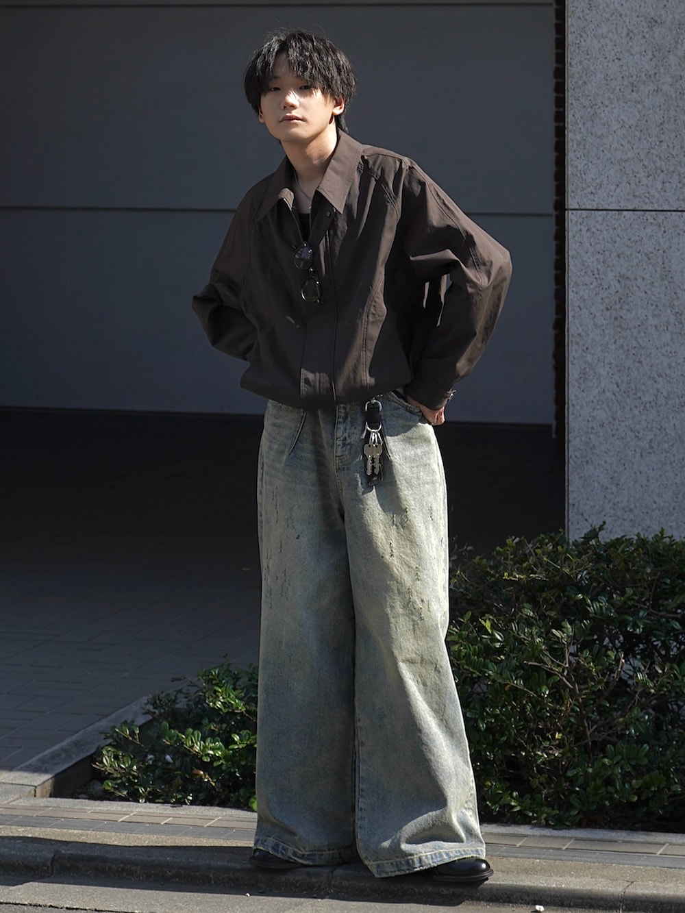 ブラウン系のブルゾン、ブラック系のタンクトップ、ブルー系のデニムパンツを着用したメンズの春コーディネートの2枚目の写真