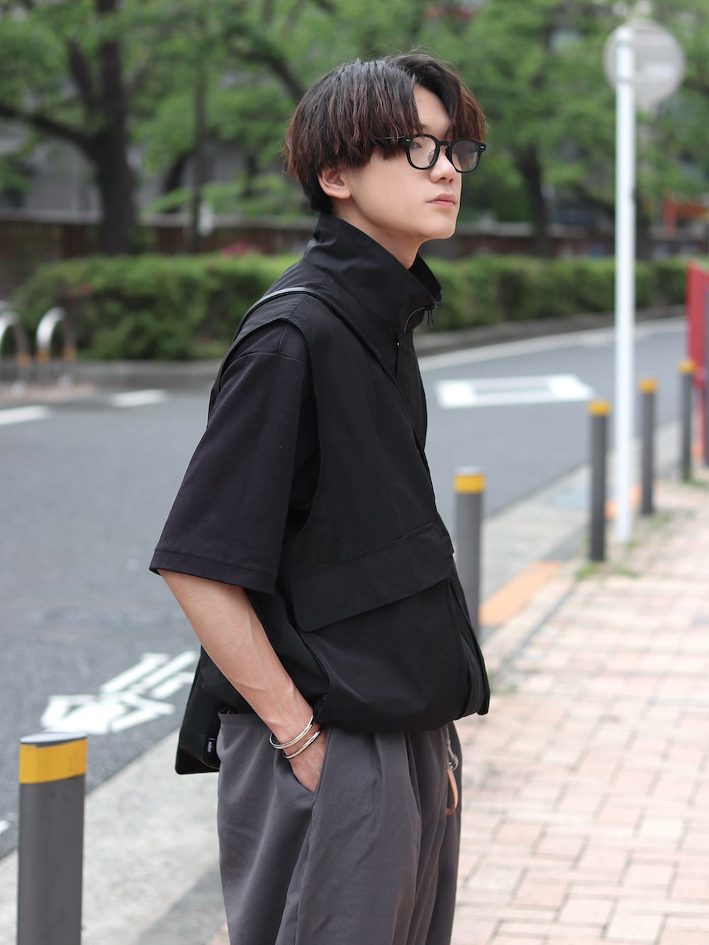 ブラック系のベスト、ブラック系のTシャツ/カットソー、グレー系のカーゴパンツを着用したメンズの春コーディネートの3枚目の写真