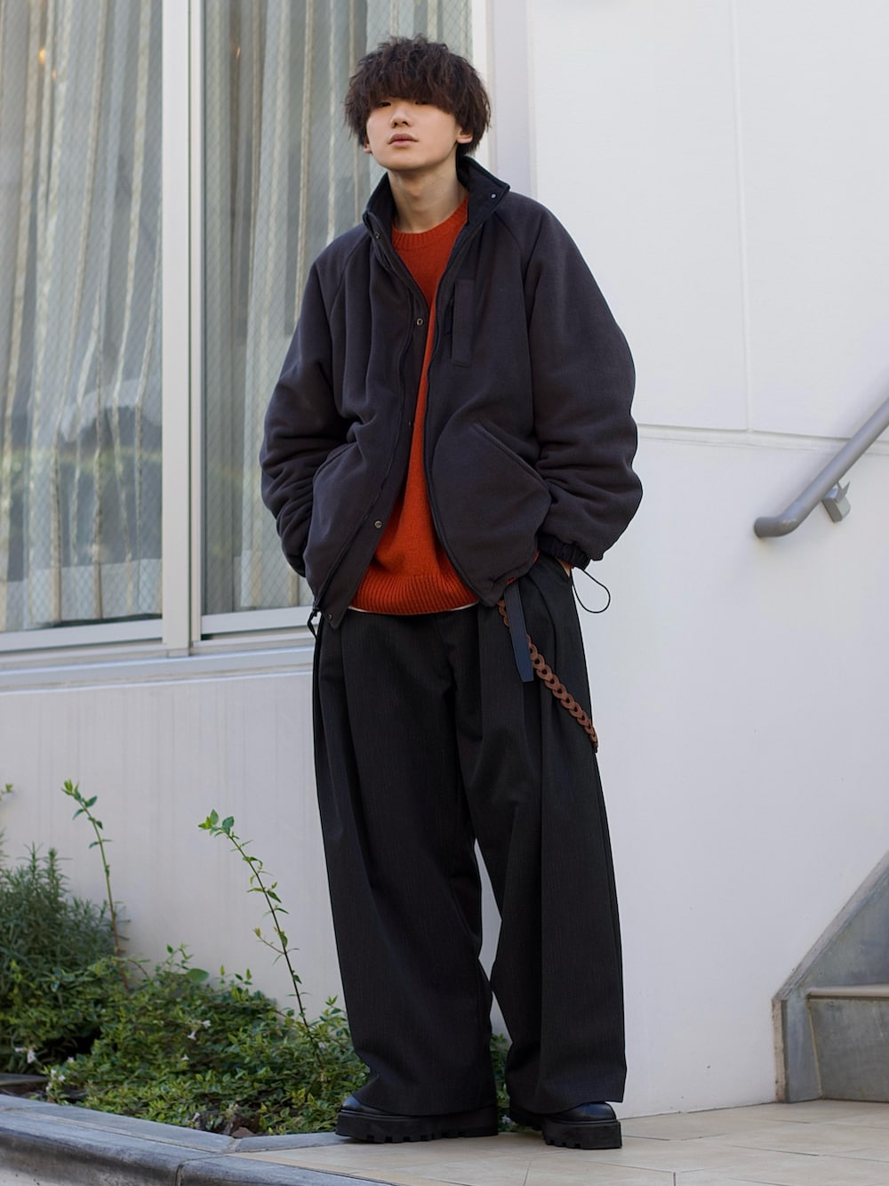 ブラック系のブルゾン、オレンジ系のニット/セーター、ホワイト系のタンクトップを着用したメンズの冬コーディネートの2枚目の写真