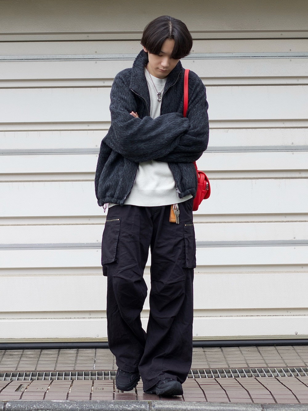 グレー系のブルゾン、ホワイト系のニット/セーター、ブラック系のカーゴパンツを着用したメンズの冬コーディネートの2枚目の写真
