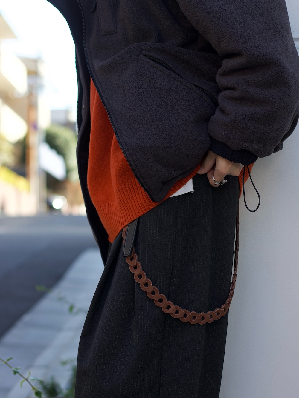 ブラック系のブルゾン、オレンジ系のニット/セーター、ホワイト系のタンクトップを着用したメンズの冬コーディネートの3枚目の写真