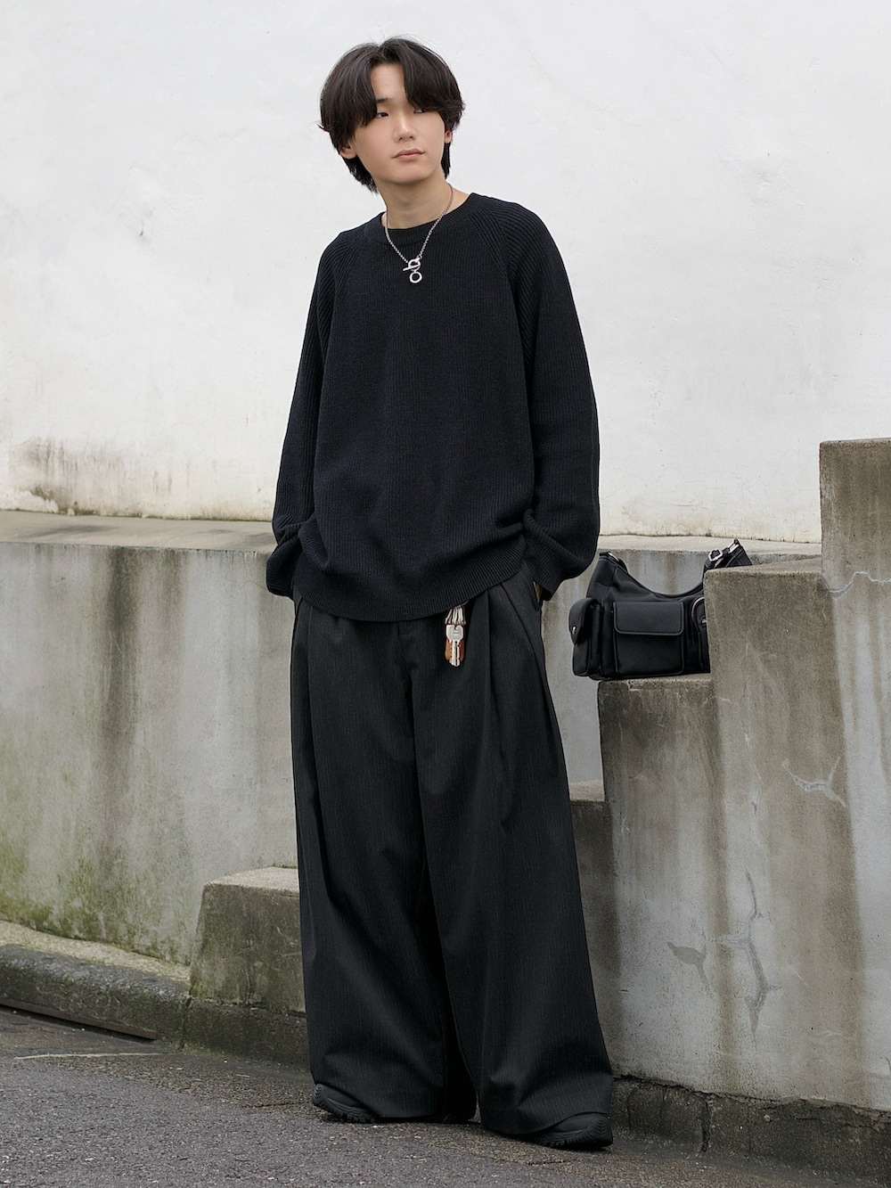 ブラック系のブルゾン、グレー系のニット/セーター、グレー系のスラックスを着用したメンズの秋コーディネートの4枚目の写真