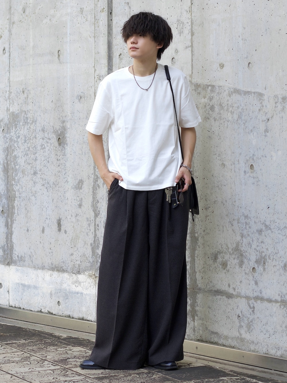 ホワイト系のTシャツ/カットソー、グレー系のスラックス、ブラック系のショルダーバッグを着用したメンズの夏コーディネートの2枚目の写真