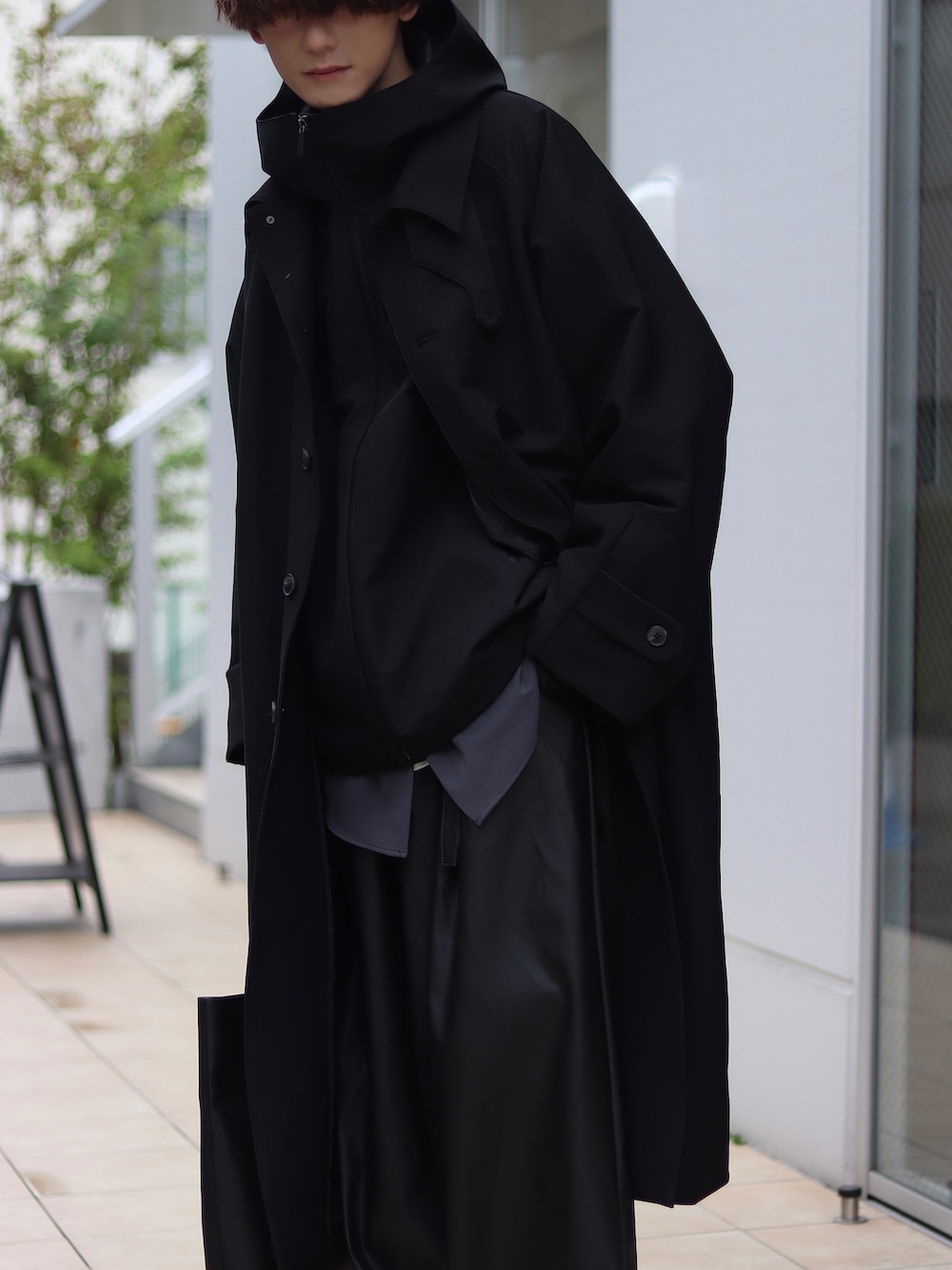 ブラック系のステンカラーコート、ブラック系のマウンテンパーカー、グレー系のシャツ/ブラウスを着用したメンズの秋コーディネートの3枚目の写真