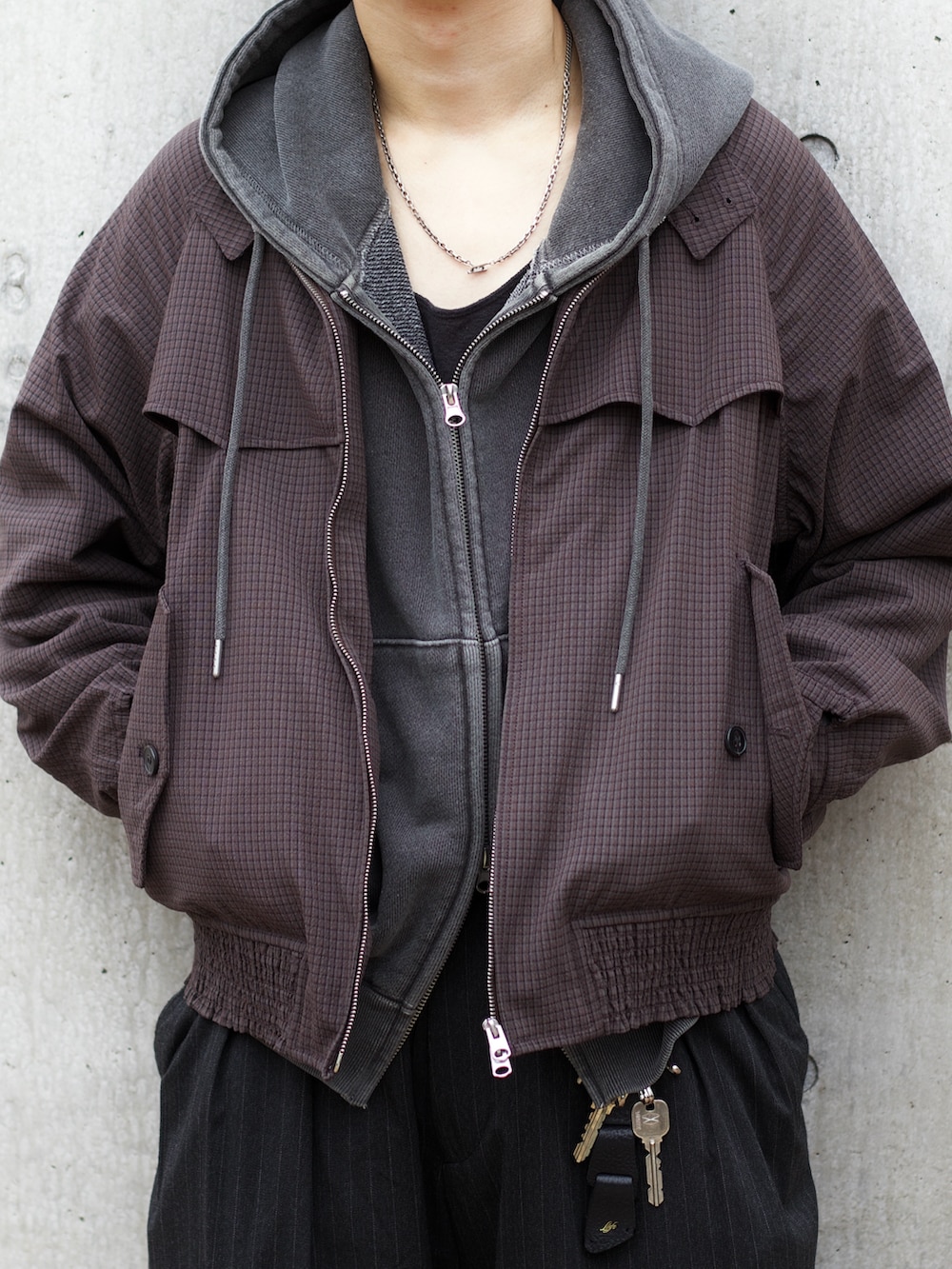 グレー系のパーカー、ブラック系のタンクトップ、ブラウン系のブルゾンを着用したメンズの秋コーディネートの3枚目の写真