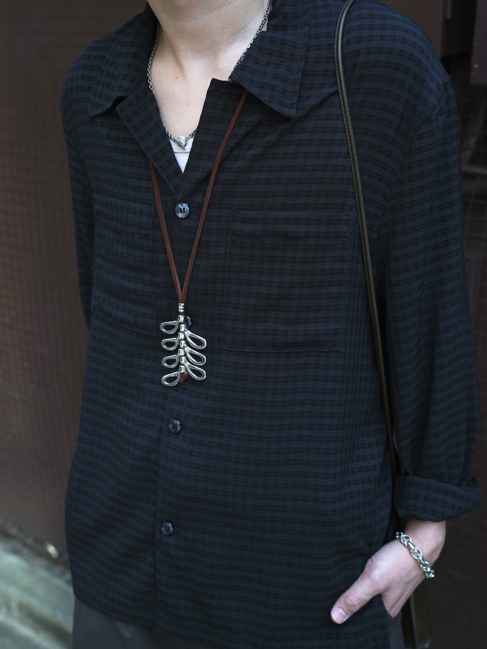 グレー系のタンクトップ、ブラック系のドレスシューズ、ブラウン系のショルダーバッグを着用したメンズの春コーディネートの3枚目の写真