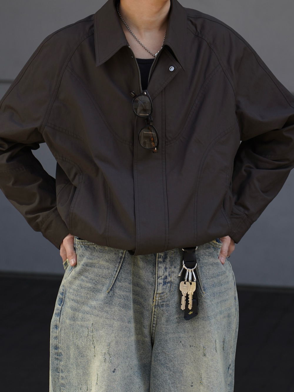 ブラウン系のブルゾン、ブラック系のタンクトップ、ブルー系のデニムパンツを着用したメンズの春コーディネートの3枚目の写真