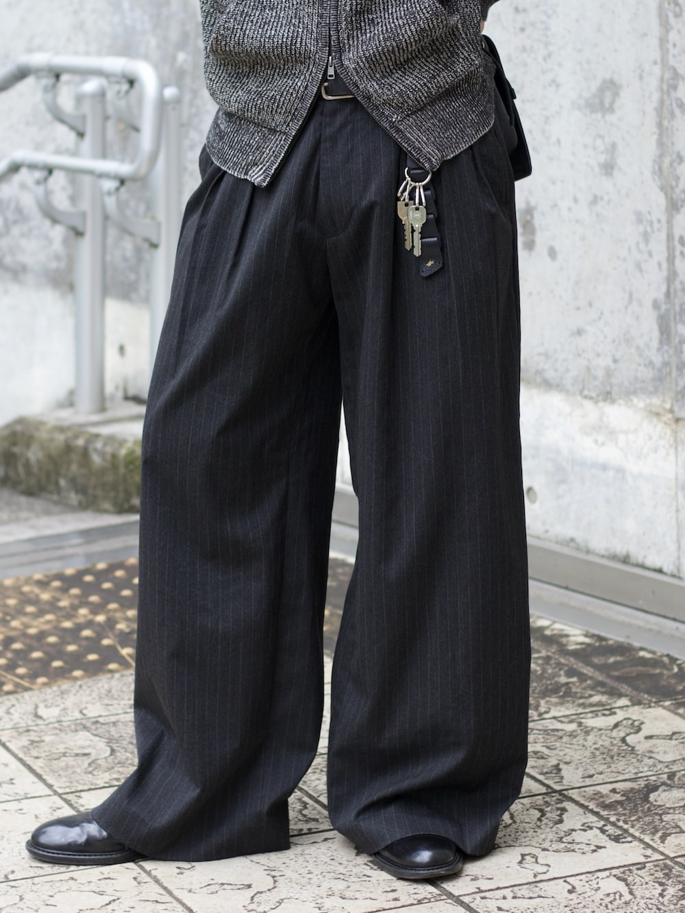 グレー系のニット/セーター、ブラック系のタンクトップ、グレー系のスラックスを着用したメンズの秋コーディネートの4枚目の写真