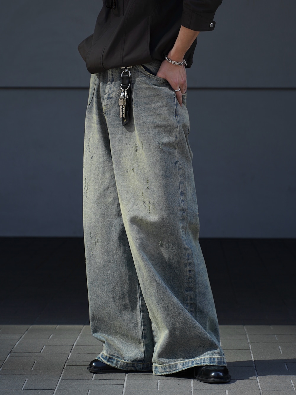 ブラウン系のブルゾン、ブラック系のタンクトップ、ブルー系のデニムパンツを着用したメンズの春コーディネートの4枚目の写真