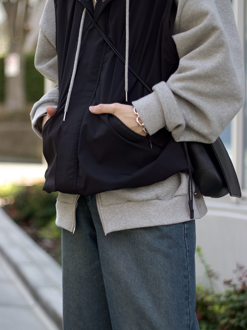 ブラック系のブルゾン、グレー系のパーカー、ブラック系のタンクトップを着用したメンズの春コーディネートの3枚目の写真