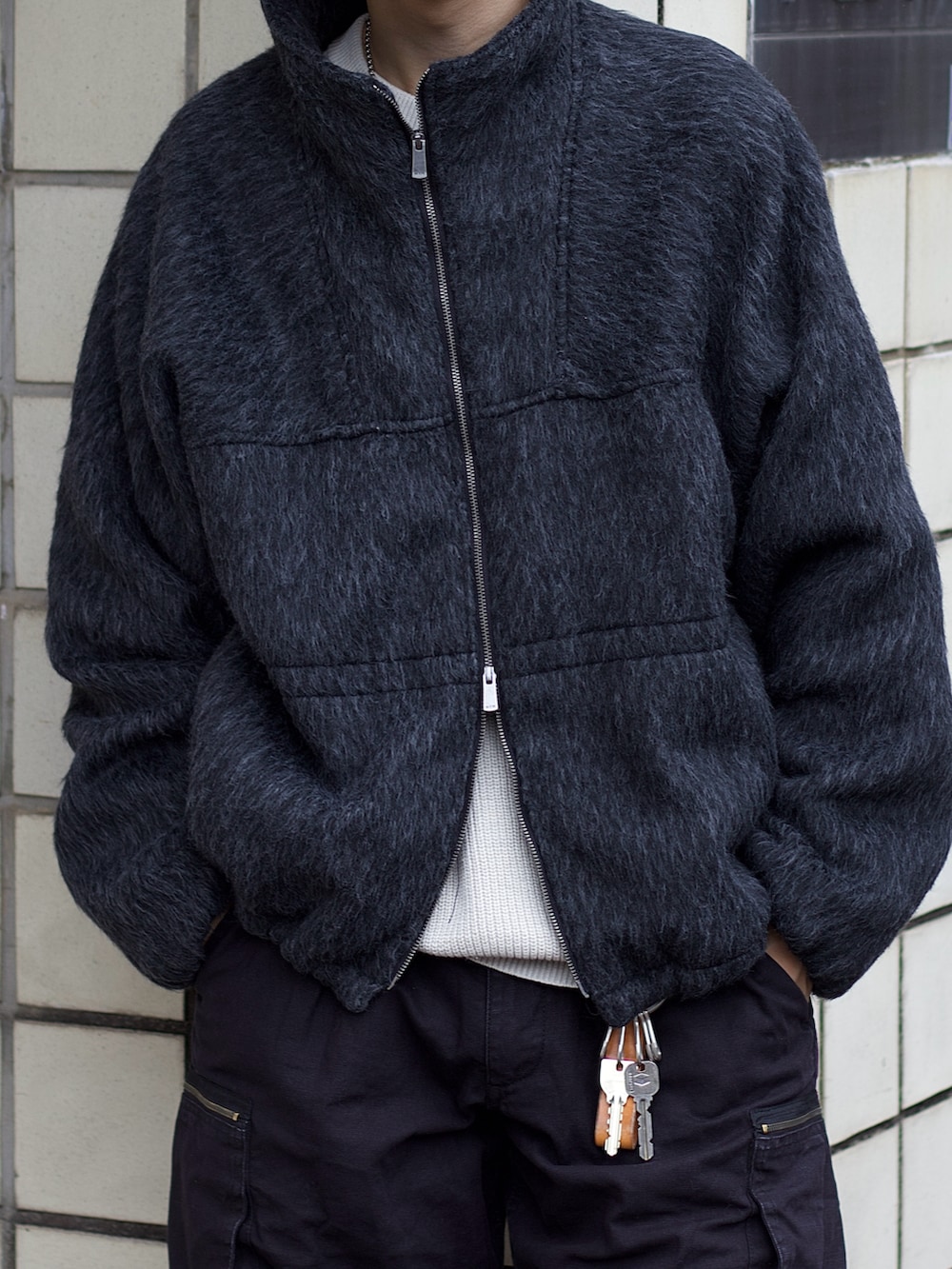 グレー系のブルゾン、ホワイト系のニット/セーター、ブラック系のカーゴパンツを着用したメンズの冬コーディネートの3枚目の写真