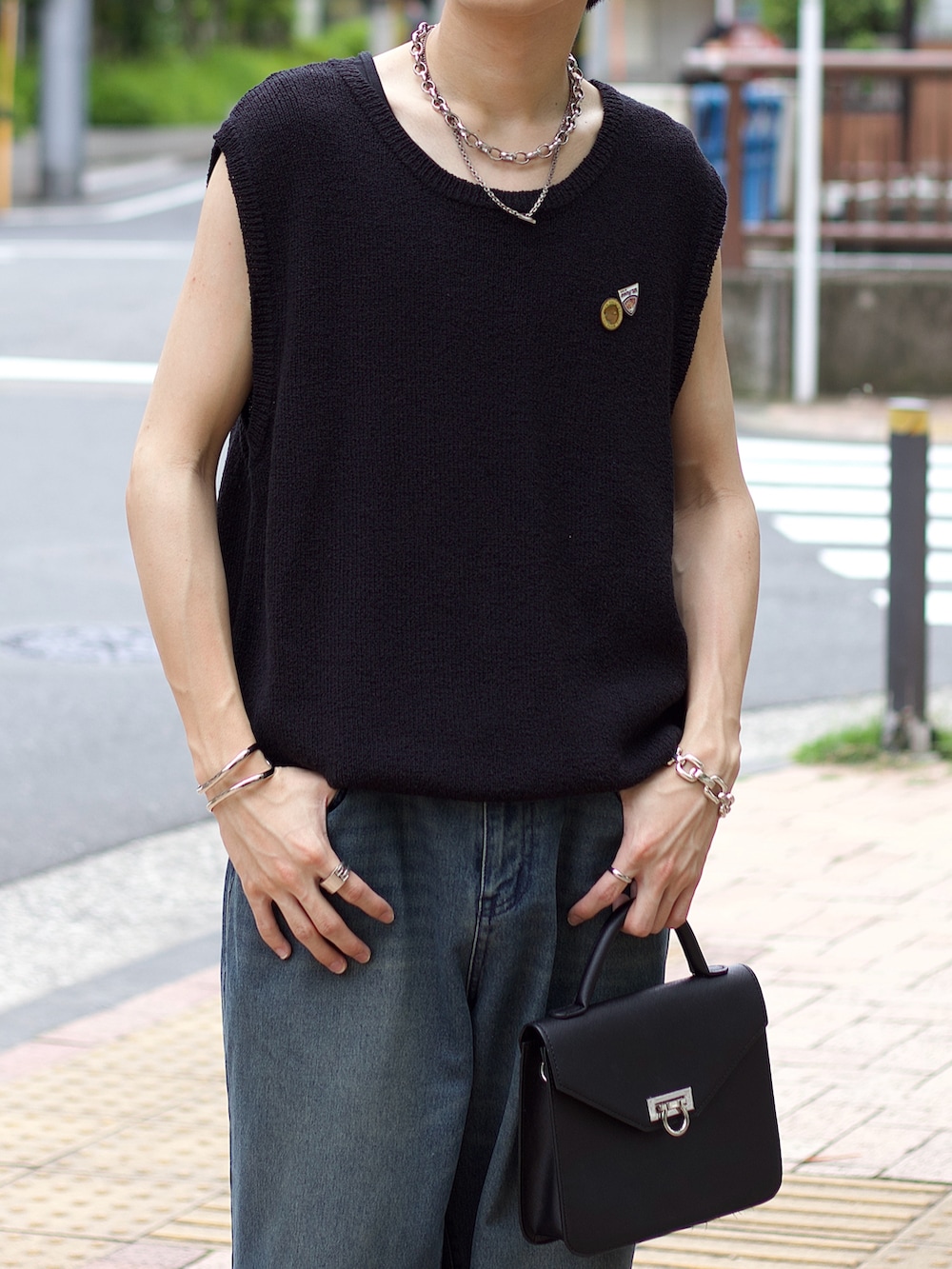 ブラック系のベスト、ブルー系のデニムパンツ、ブラック系のスニーカーを着用したメンズの夏コーディネートの3枚目の写真