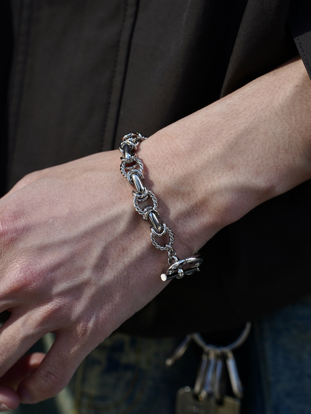 ブラウン系のブルゾン、ブラック系のタンクトップ、ブルー系のデニムパンツを着用したメンズの春コーディネートの5枚目の写真