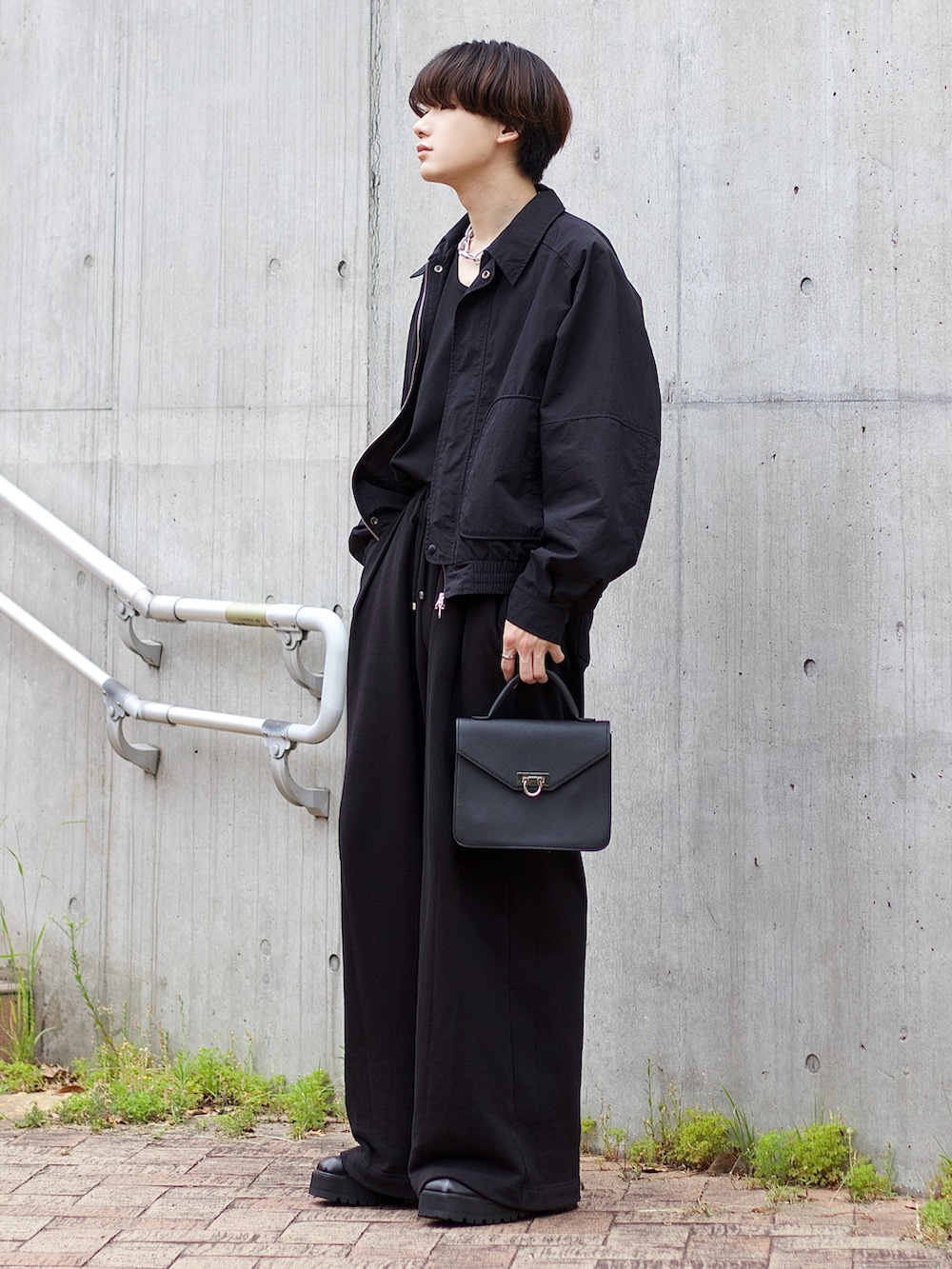 ブラック系のテーラードジャケット、ブラック系のタンクトップ、ブラック系のスウェットパンツを着用したメンズの春コーディネートの2枚目の写真