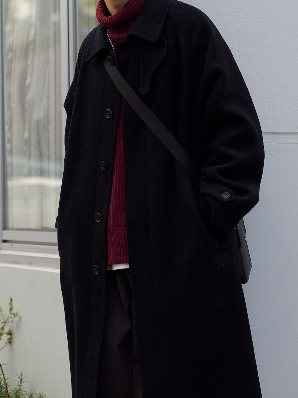 ブラック系のステンカラーコート、レッド系のニット/セーター、ホワイト系のタンクトップを着用したメンズの冬コーディネートの3枚目の写真