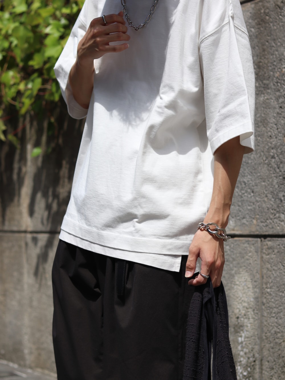 ホワイト系のTシャツ/カットソー、ホワイト系のタンクトップ、グレー系のスラックスを着用したメンズの夏コーディネートの4枚目の写真