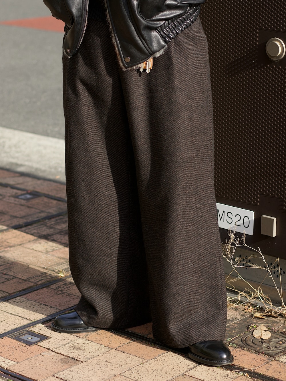 ブラック系のその他アウター、ブラック系のニット/セーター、ブラウン系のスラックスを着用したメンズの冬コーディネートの4枚目の写真