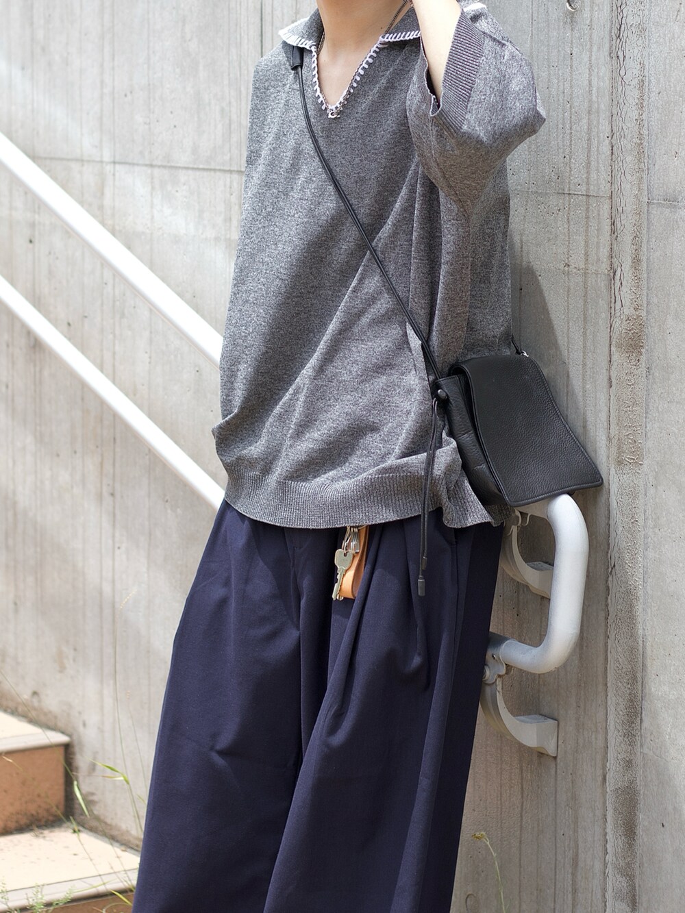 ブラック系のポロシャツ、ブルー系のスラックス、ブラック系のスニーカーを着用したメンズの夏コーディネートの3枚目の写真