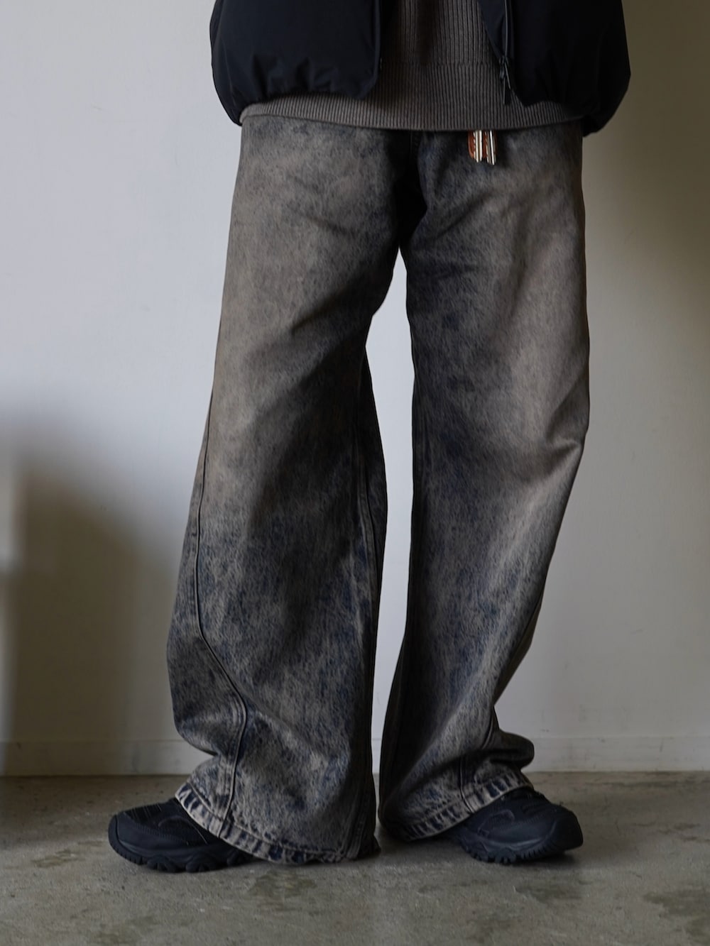 ブラック系のダウンジャケット/コート、ブラウン系のニット/セーター、ブルー系のデニムパンツを着用したメンズの秋コーディネートの3枚目の写真