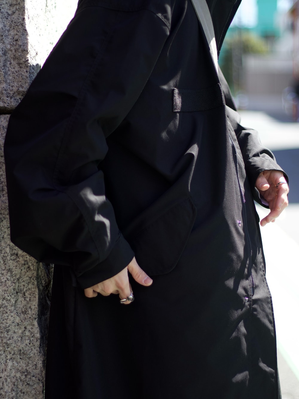 ブラック系のモッズコート、グレー系のベスト、ホワイト系のタンクトップを着用したメンズの春コーディネートの3枚目の写真