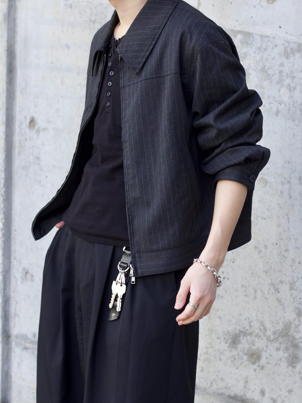 ブラック系のニット/セーター、グレー系のブルゾン、ブラック系のスラックスを着用したメンズの冬コーディネートの2枚目の写真