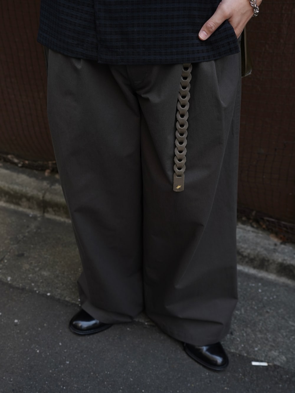 グレー系のタンクトップ、ブラック系のドレスシューズ、ブラウン系のショルダーバッグを着用したメンズの春コーディネートの4枚目の写真