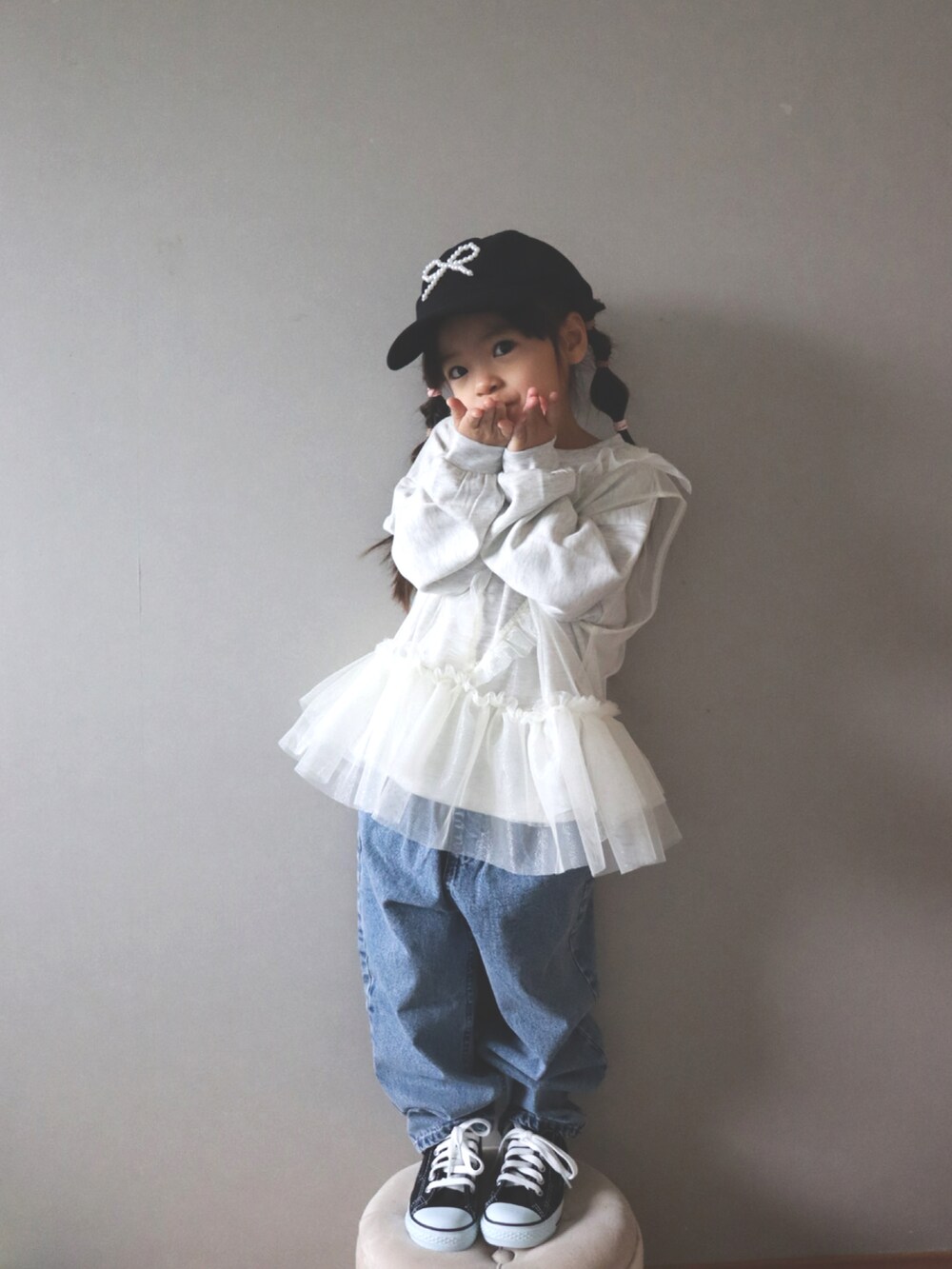 ホワイト系のスウェット、ブルー系のデニムパンツ、ブラック系のキャップを着用したキッズの冬コーディネートの2枚目の写真