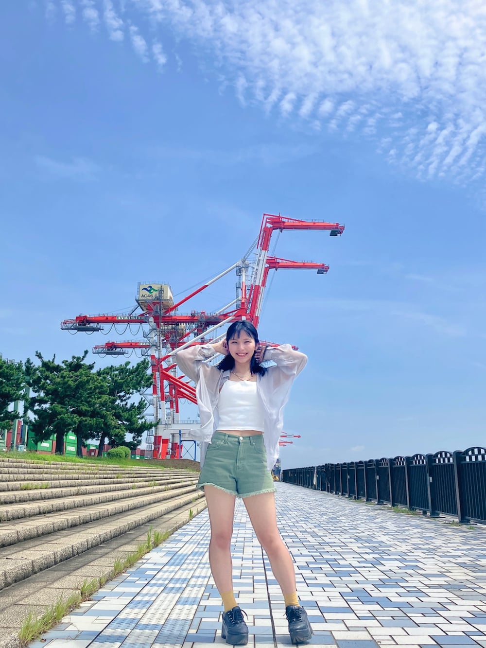 ホワイト系のタンクトップ、グリーン系のデニムパンツ、ブラック系のスニーカーを着用したレディースの夏コーディネートの2枚目の写真