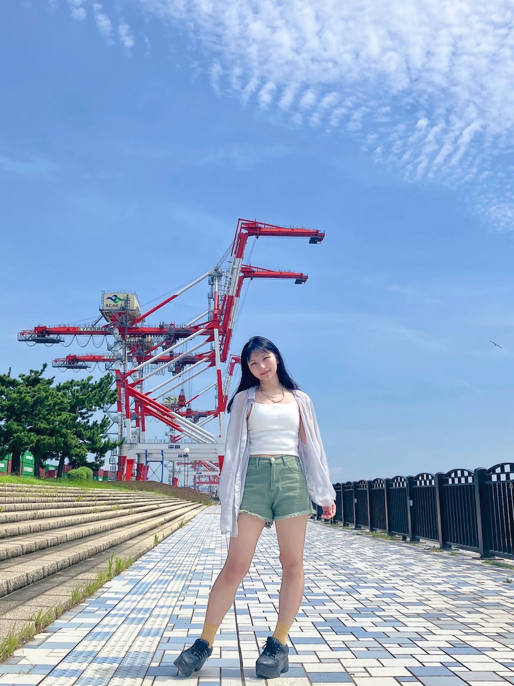 ホワイト系のタンクトップ、グリーン系のデニムパンツ、ブラック系のスニーカーを着用したレディースの夏コーディネートの3枚目の写真