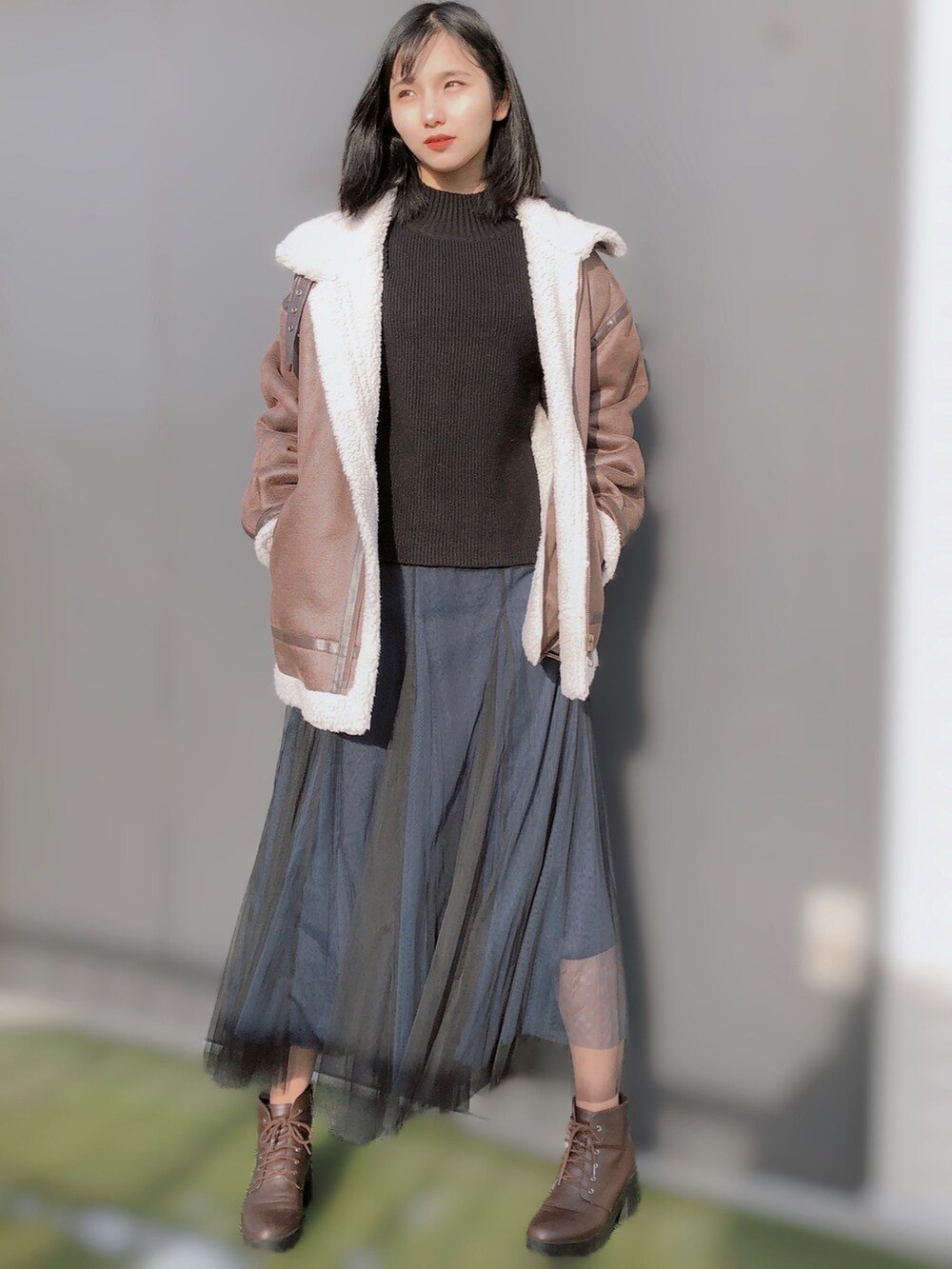 ブラック系のニット/セーター、ブラウン系のムートンコート、ブルー系のスカートを着用したレディースの冬コーディネートの2枚目の写真