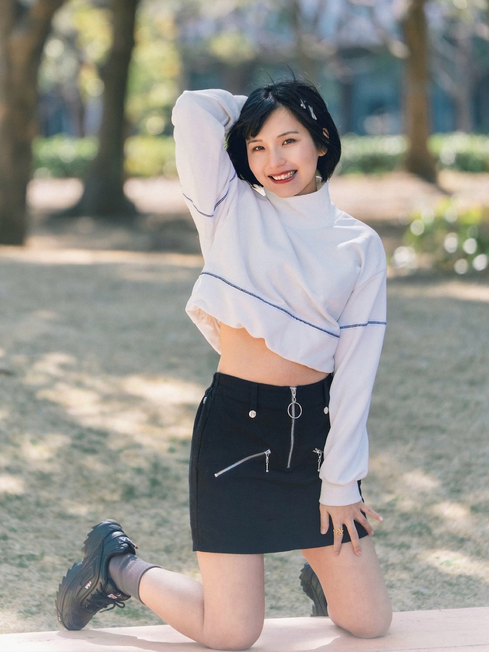 ホワイト系のスウェット、ブラック系のスカート、ブラック系のスニーカーを着用したレディースの春コーディネートの2枚目の写真