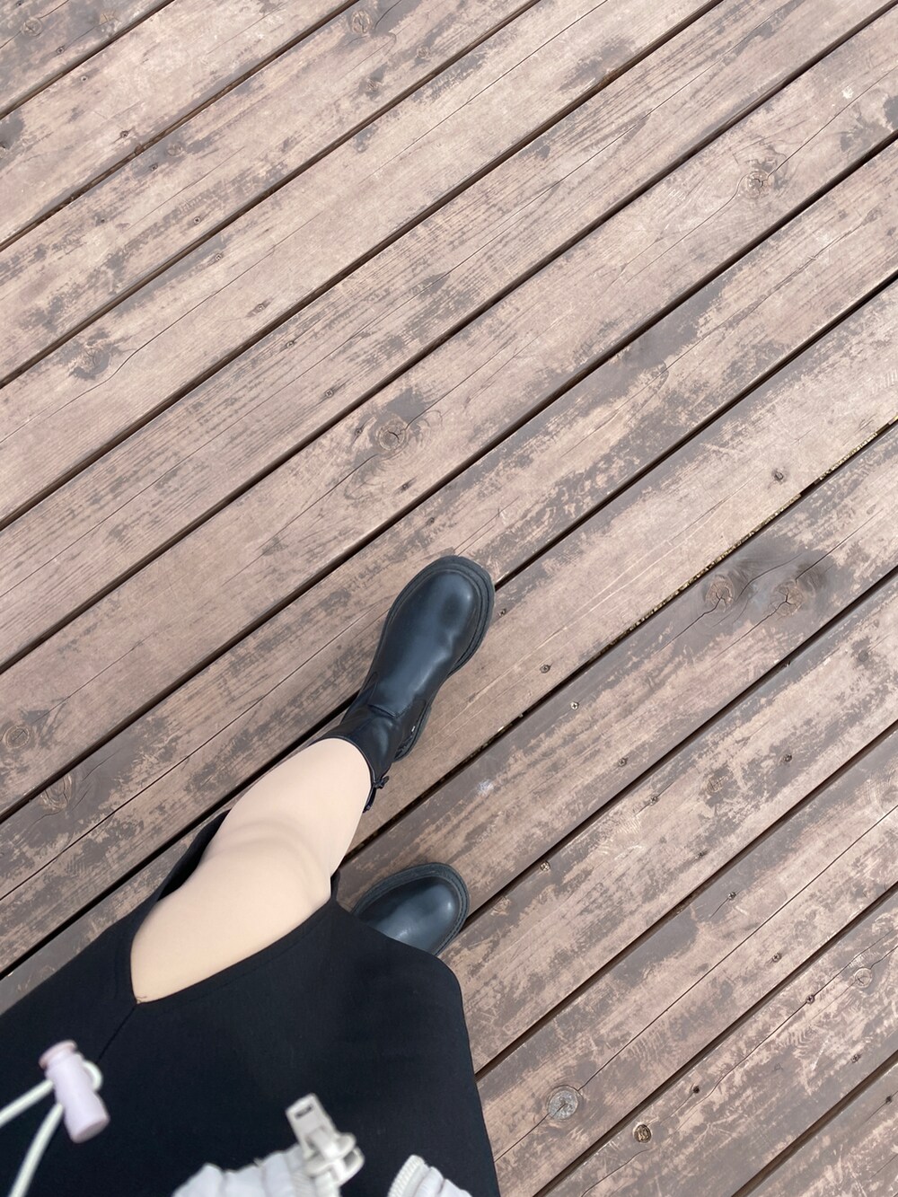 ホワイト系のダウンジャケット/コート、ブラック系のブーツ、ブラック系のショルダーバッグを着用したレディースの春コーディネートの2枚目の写真