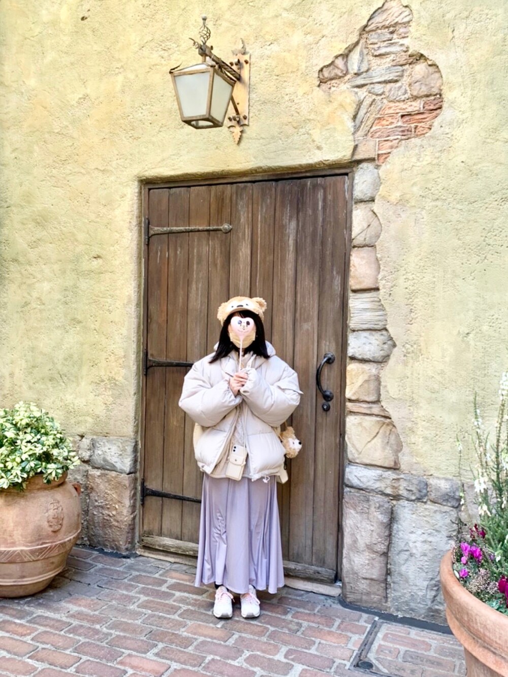 ホワイト系のダウンジャケット/コート、パープル系のスカート、グレー系のニット/セーターを着用したレディースの春コーディネートの2枚目の写真