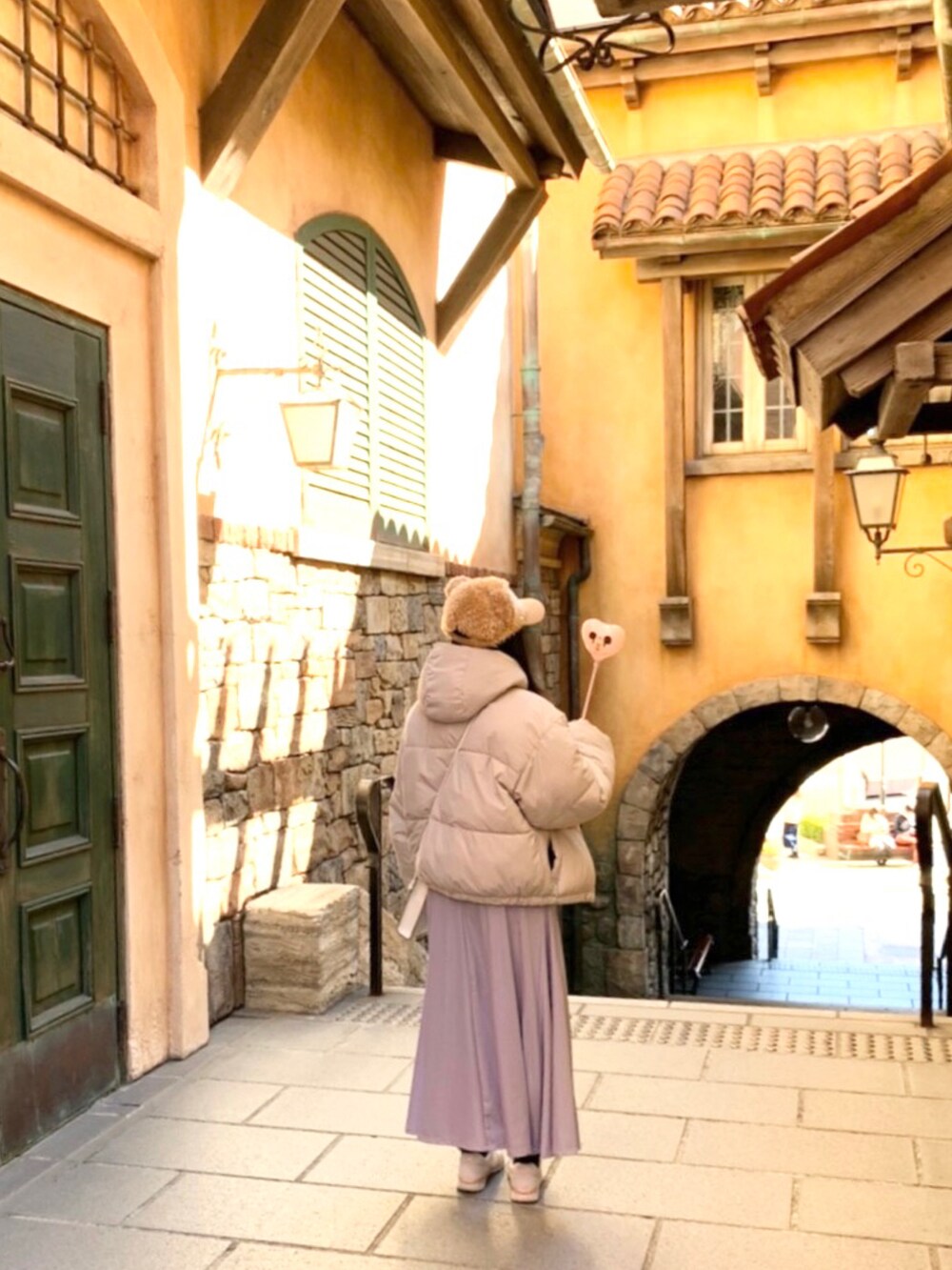 ホワイト系のダウンジャケット/コート、パープル系のスカート、グレー系のニット/セーターを着用したレディースの春コーディネートの3枚目の写真