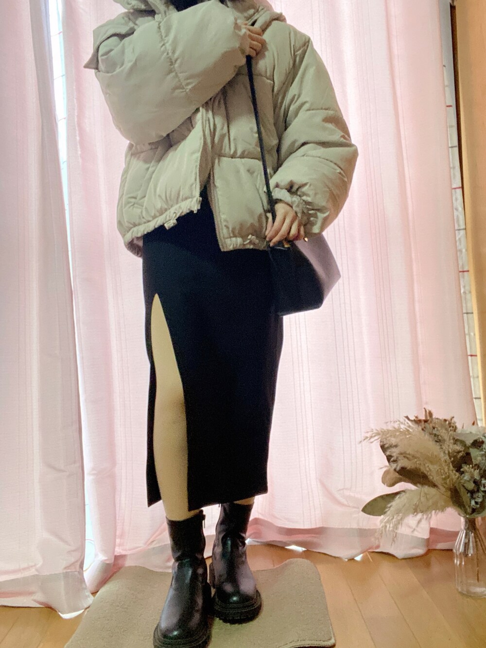 ホワイト系のダウンジャケット/コート、ブラック系のブーツ、ブラック系のショルダーバッグを着用したレディースの春コーディネートの3枚目の写真