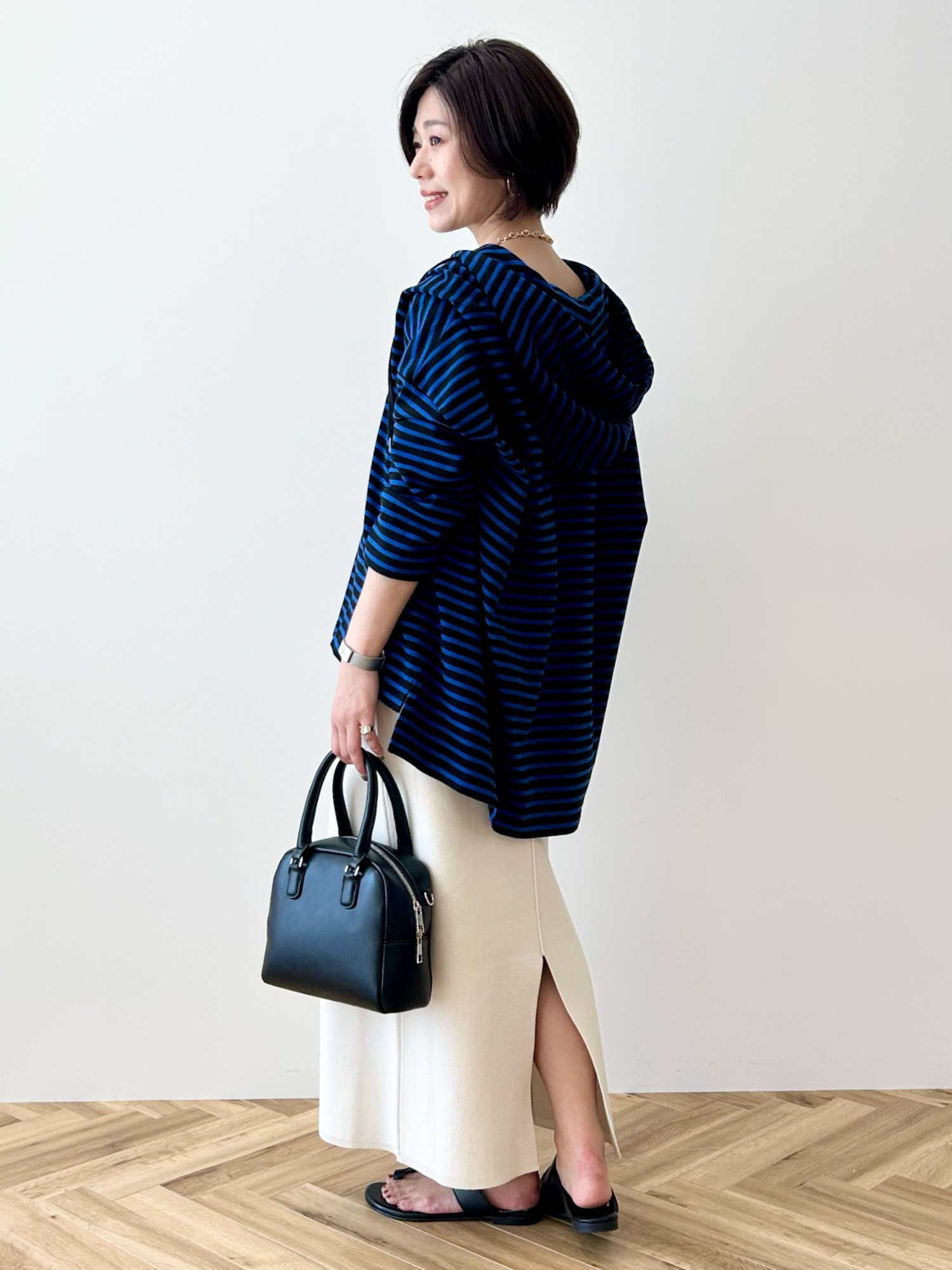 ブルー系のチュニック、ホワイト系のスカート、ブラック系のボストンバッグを着用したレディースの春コーディネートの5枚目の写真